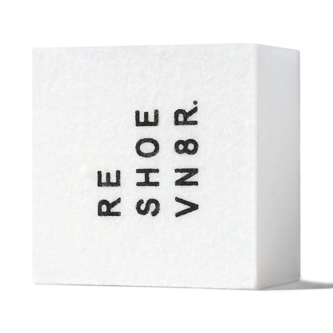 A white shoe cleaning sponge with black text that says "RESHOEVN8R" sitting on a white surface.