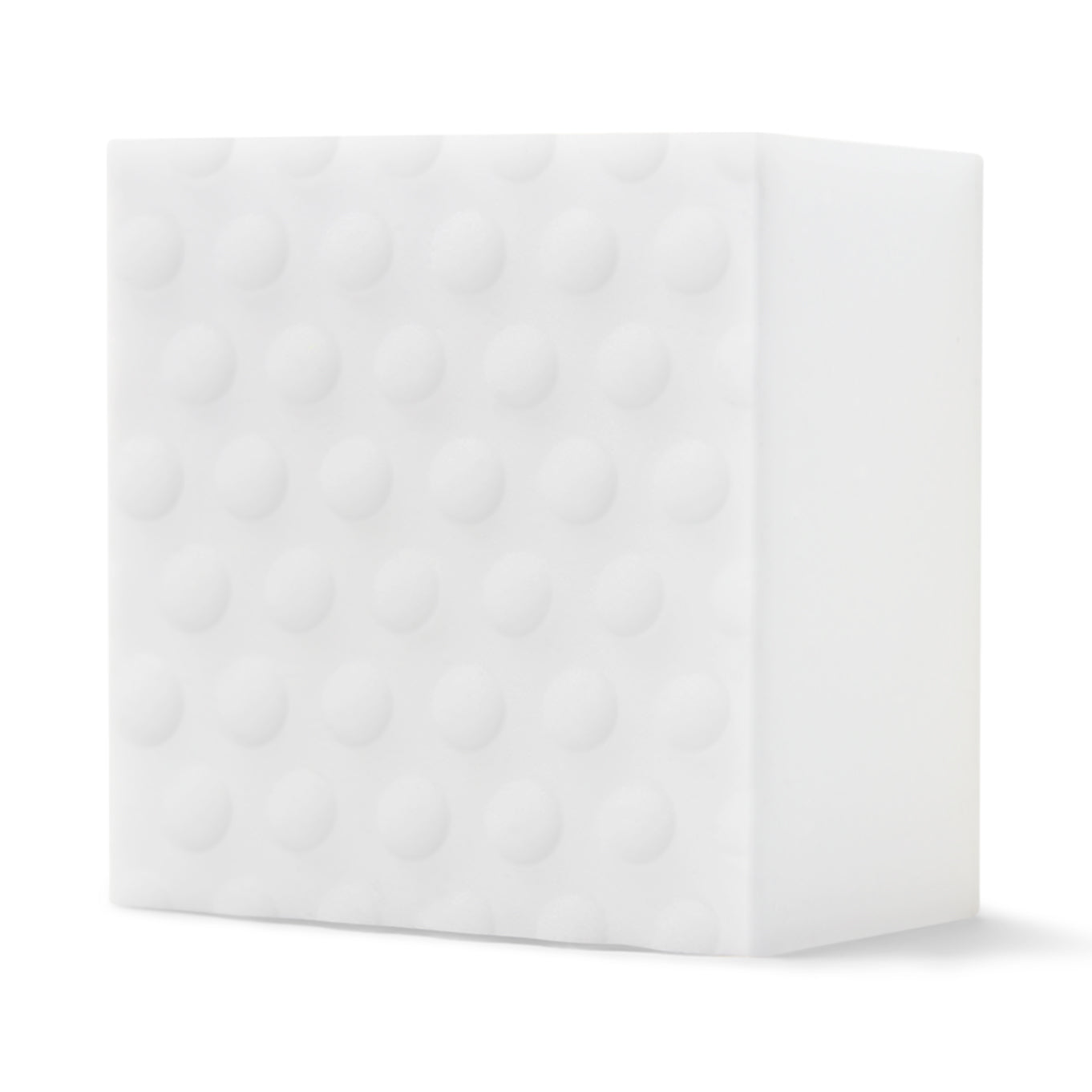 A white shoe cleaning sponge with textured bumps sitting on a white surface.