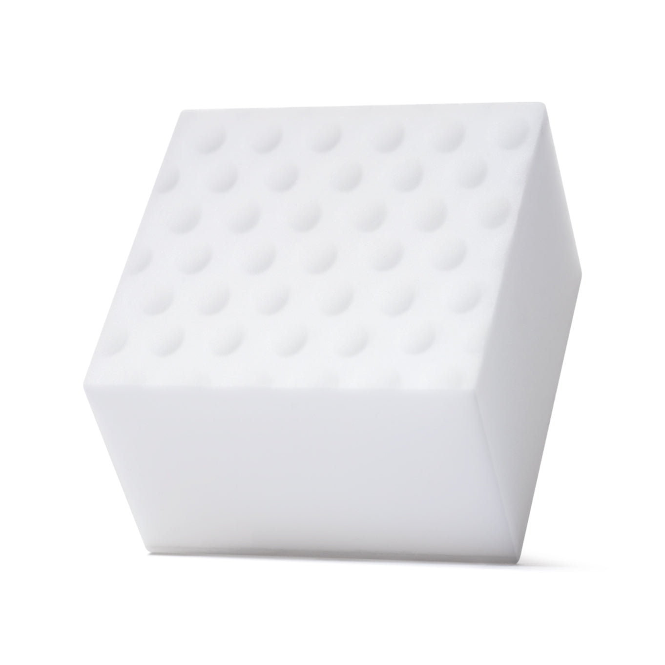 A white shoe cleaning sponge with textured bumps sitting on a white surface.
