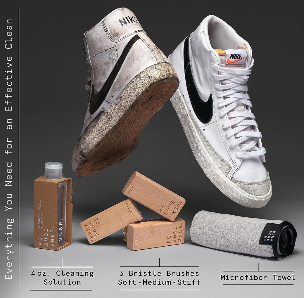 A pair of white Nike Blazer sneakers sitting on top of a box of Reshoevn8r shoe cleaning supplies. The cleaning supplies include a bottle of cleaning solution, three bristle brushes in different softness levels, and a microfiber towel. One sneaker is clean, and the other is dirty.